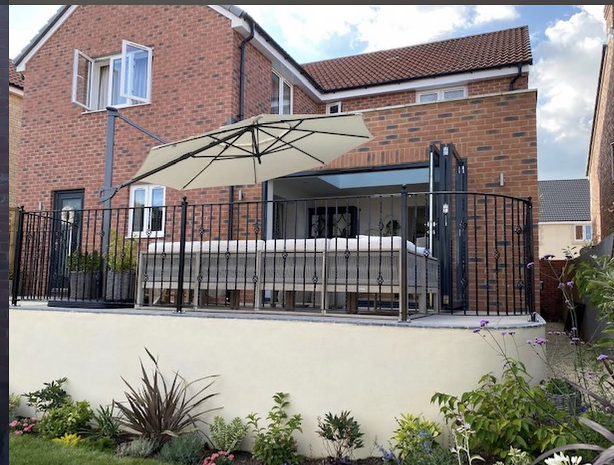 Curved decorative wrought-iron balcony railing outside bi-fold doors.
