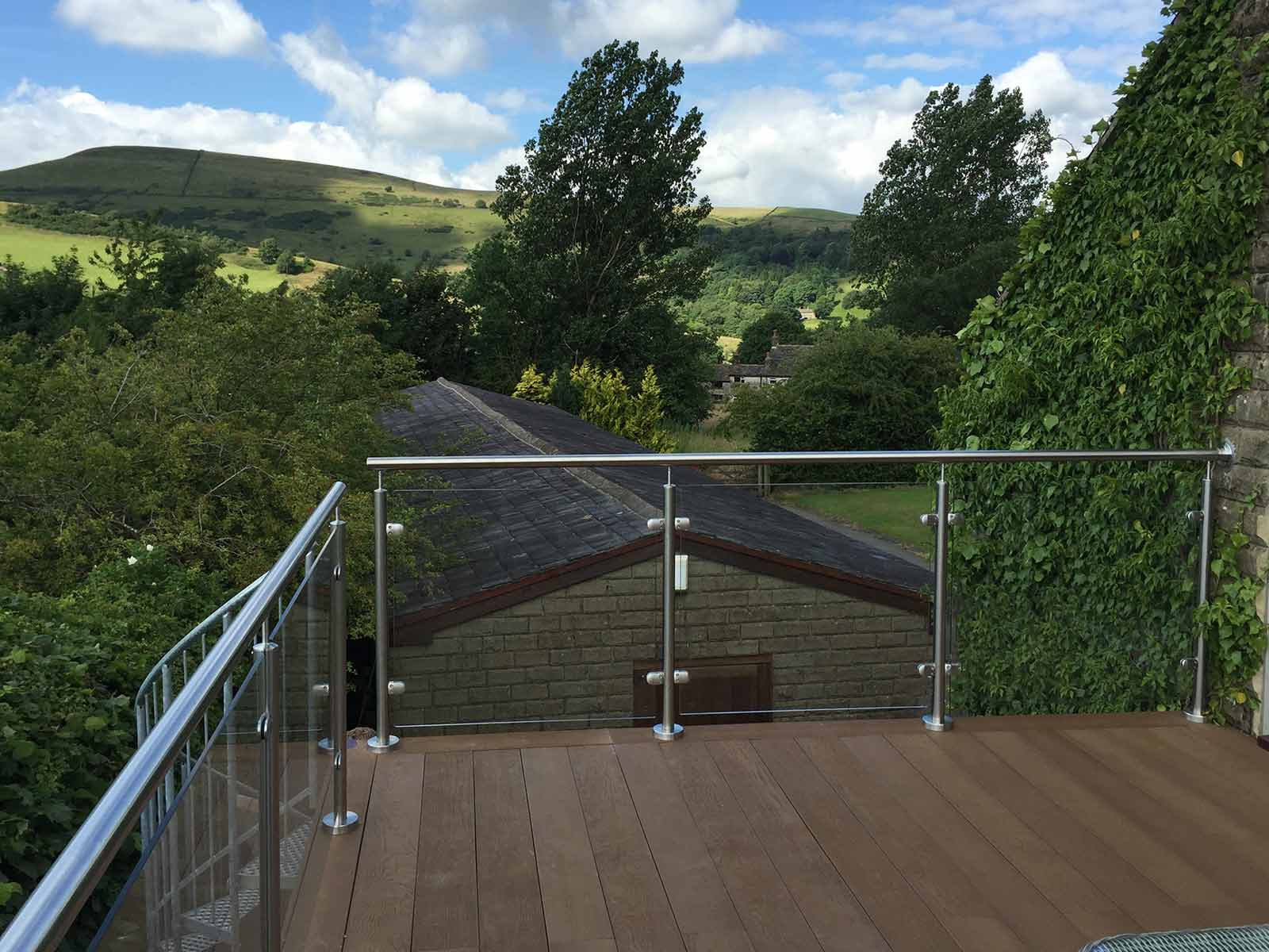 Stainless steel and glass balcony balustrade overlooking open countryside.