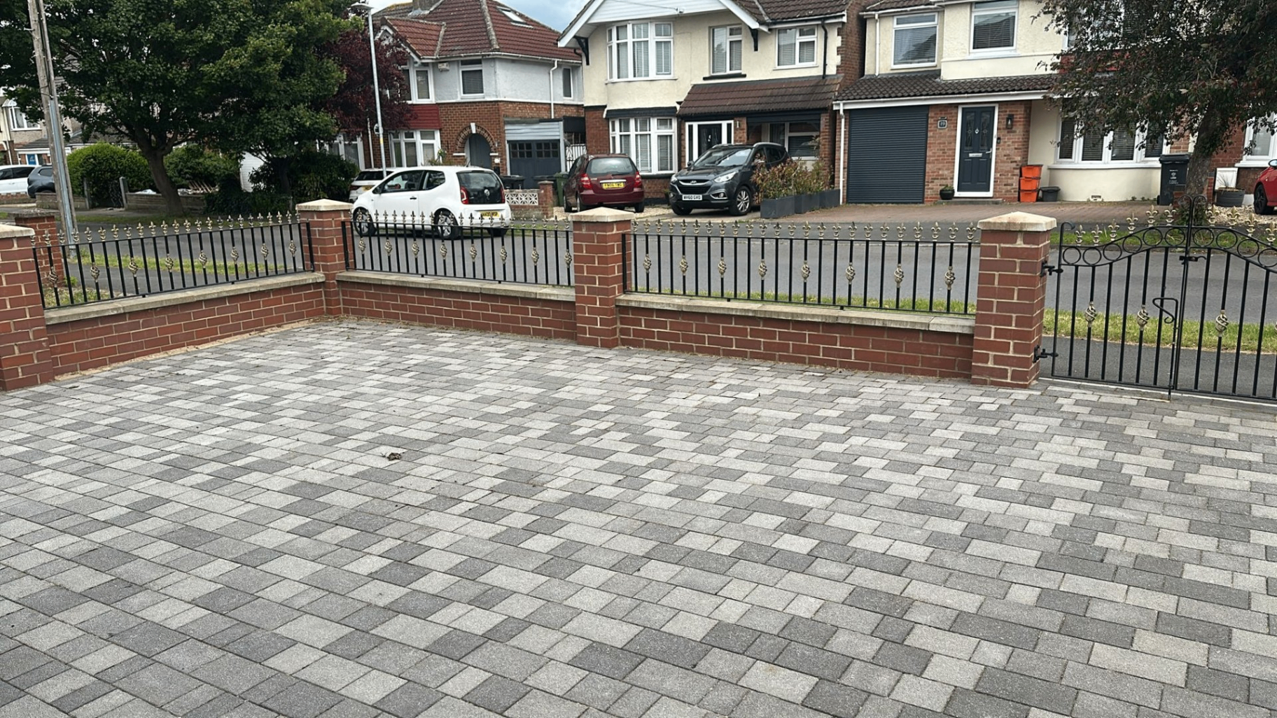 Wrought-iron front garden railings and side gate mounted on brick pillars.