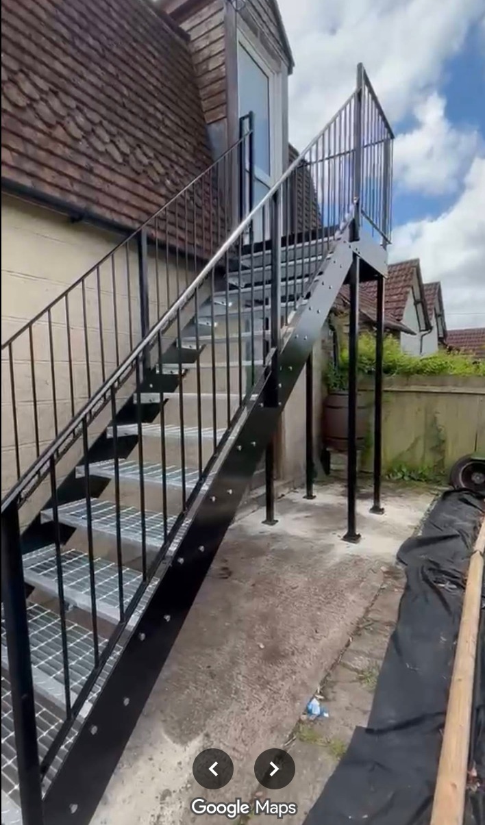 External steel fire-escape staircase with mesh treads and black railings.